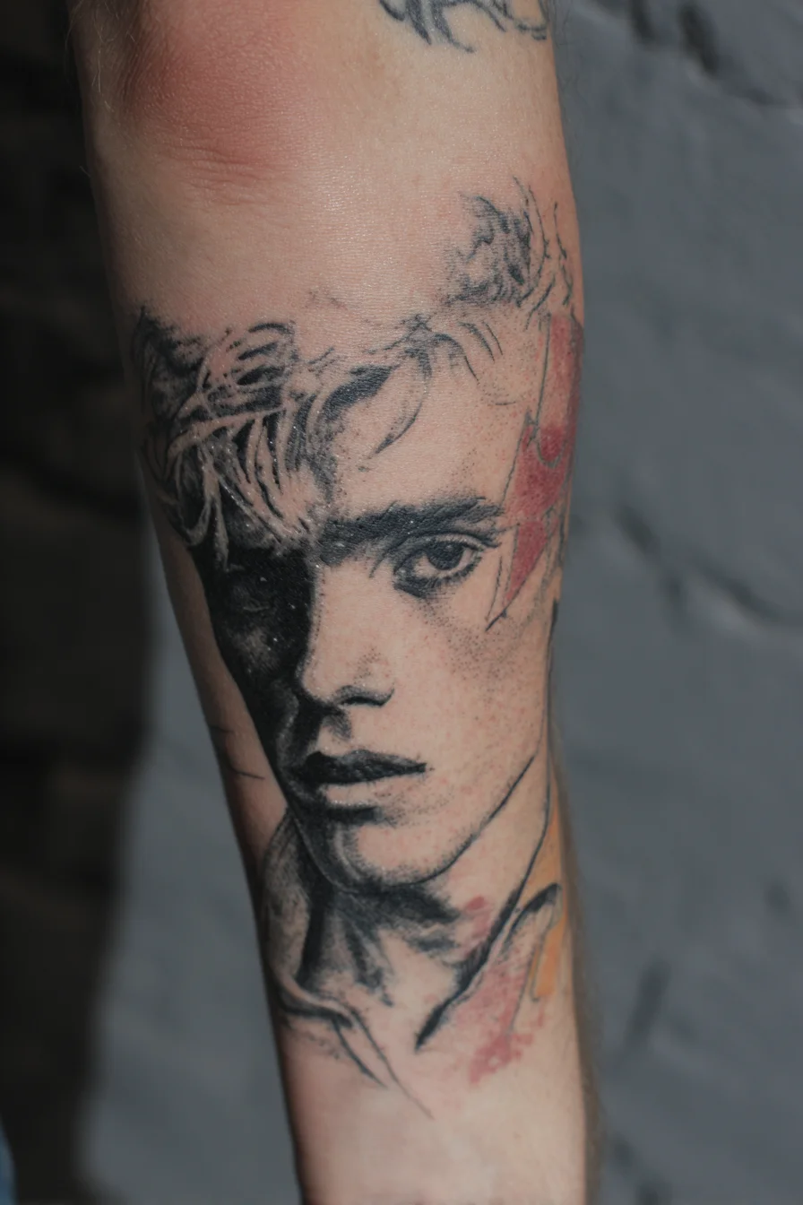 Realistic Black & Grey Portrait Tattoo — Forearm Placement with Watercolor Accents